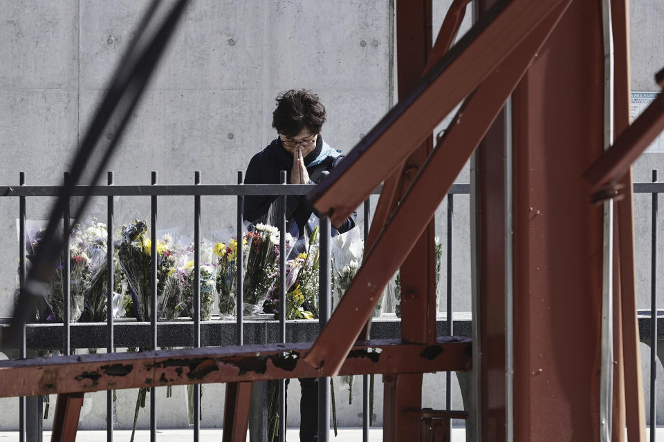 A woman prays at the skeleton of the tsunami-damaged disaster prevention headquarters where dozens of workers died in the 2011 tsunami in Minamisanriku, Miyagi Prefecture, northern Japan Monday, March 11, 2024. Japan marked the 13th anniversary of the massive earthquake, tsunami and nuclear disaster. (Kyodo News via AP)