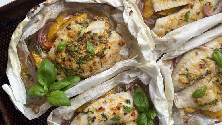 four tilapia fish fillets baked in parchment papillote on baking dish