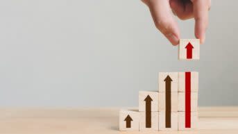 Hand arranging wood block stacking as step stair with arrow up.