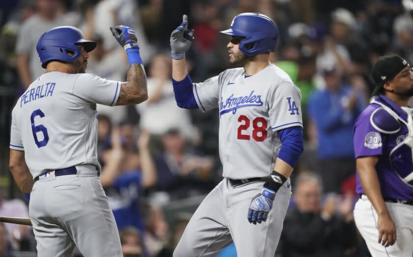 Los Angeles Dodgers' David Peralta, left, congratulates J.D. Martinez after his two-run home run off Colorado Rockies relief pitcher Peter Lambert during the fourth inning of a baseball game Thursday, June 29, 2023, in Denver. (AP Photo/David Zalubowski)
