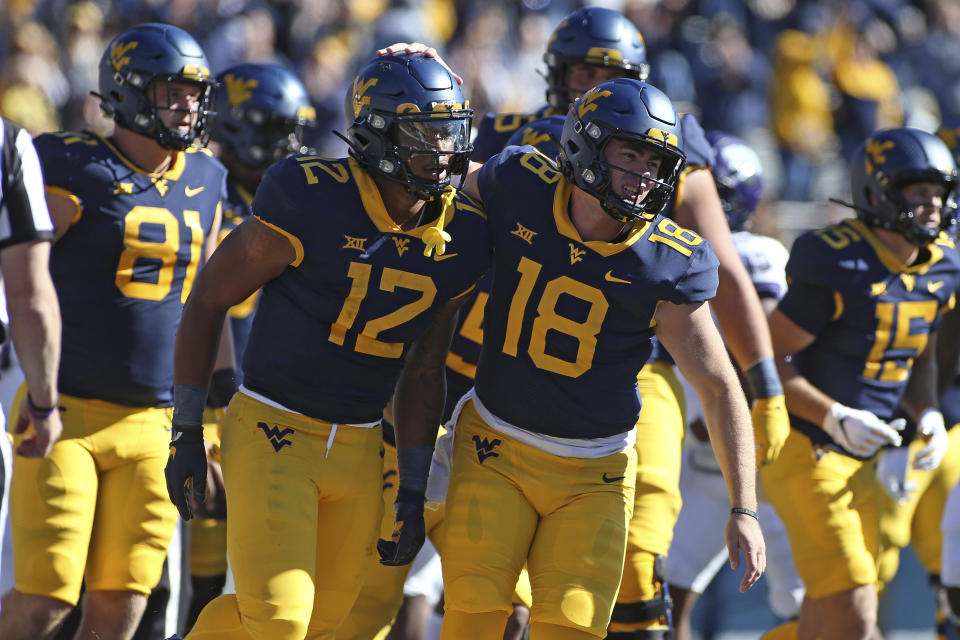 West Virginia running back CJ Donaldson (12) and quarterback JT Daniels (18) celebrate during the first half of an NCAA college football game against TCU in Morgantown, W.Va., Saturday, Oct. 29, 2022. (AP Photo/Kathleen Batten)