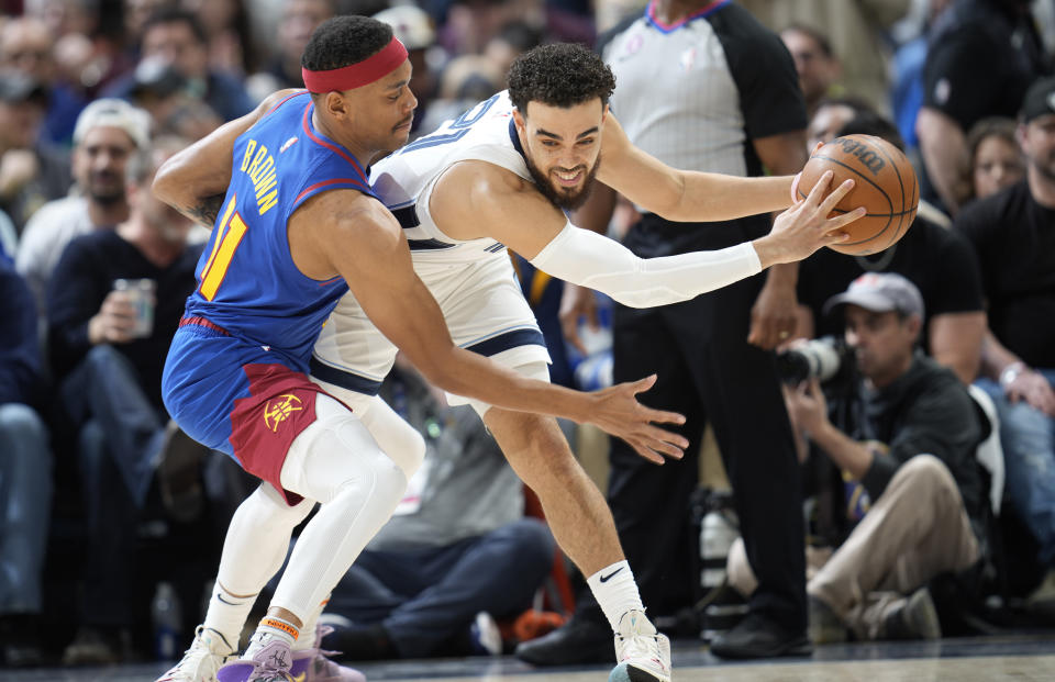 Memphis Grizzlies guard Tyus Jones, right, looks to pass the ball as Denver Nuggets forward Bruce Brown defends in the first half of an NBA basketball game Friday, March 3, 2023, in Denver. (AP Photo/David Zalubowski)