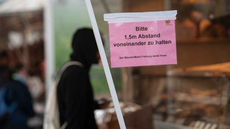 20.03.2020, Baden-Württemberg, Freiburg: Ein Mann kauft auf dem Münstermarkt ein. Am Stand ist ein Schild angebracht mit der Aufschrift 