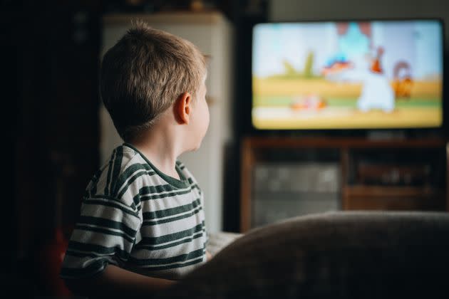 Rear view of cute boy sitting on sofa watching TV