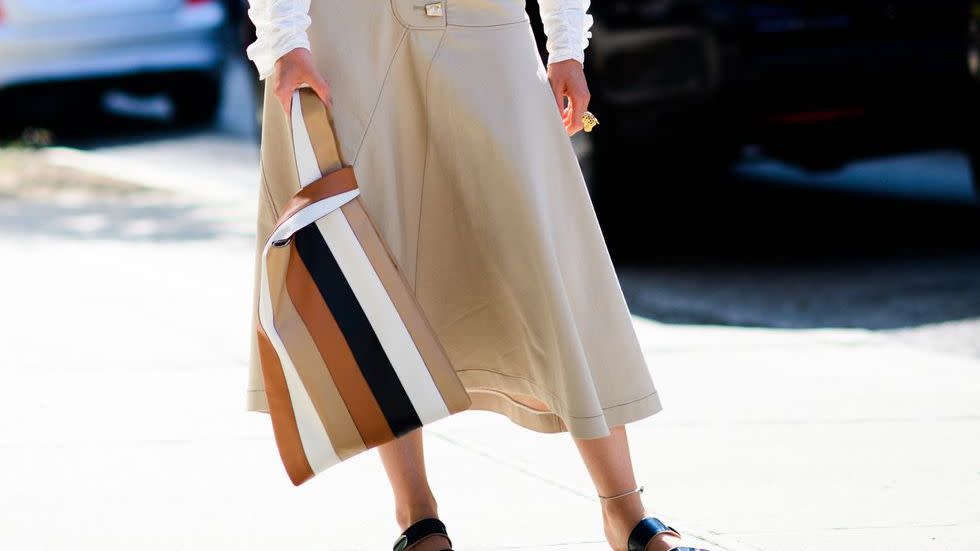 a model wears a white blouse and a khaki skirt