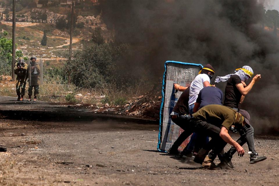 May 20, 2022: Palestinians take cover behind a makeshift barrier during clashes with Israeli forces following a demonstration against the expropriation of Palestinian land by Israel in the village of Kfar Qaddum near the Jewish settlement of Kedumim in the occupied West Bank.