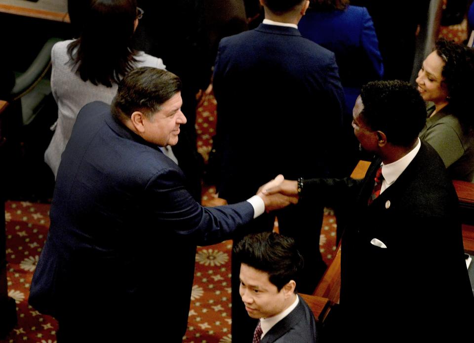 Illinois Gov. JB Pritzker shakes hands with House members as he enters the House chamber Wednesday, February 21, 2024