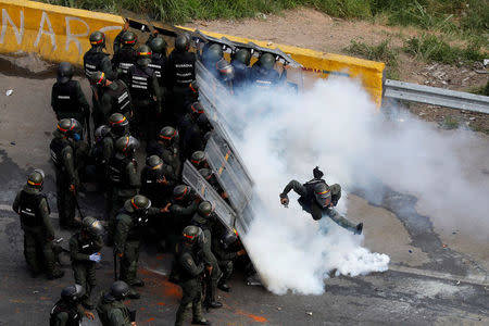 A riot security forces member kicks a tear gas canister during protests at a march to state Ombudsman's office in Caracas, Venezuela. REUTERS/Carlos Garcia Rawlins