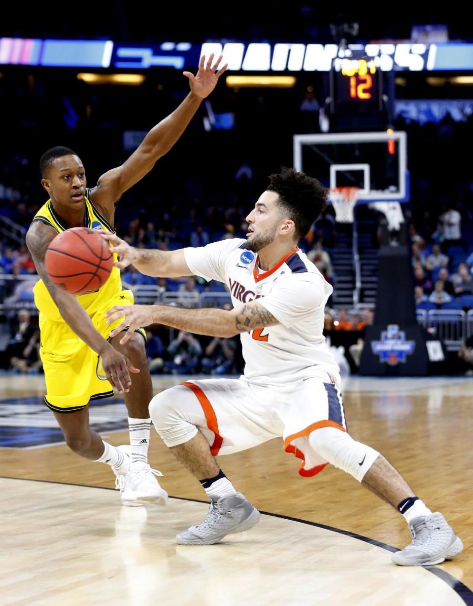 Virginia guard London Perrantes, right, passes past UNC Wilmington guard C.J. Bryce during the first round of the NCAA college basketball tournament, Thursday, March 16, 2017 in Orlando, Fla. (AP Photo/Wilfredo Lee)