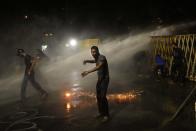 Protestors run for cover as police fire tear gas shells near the president's official residence in Colombo, Sri Lanka, Saturday, May 28, 2022. Police fired tear gas and water canon on protesters who marched toward the president Gotabaya Rajapaksa's barricaded residence demanding his resignation. (AP Photo/Eranga Jayawardena)