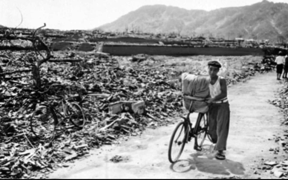 FILE - In this September 1945, file photo, a Japanese man pushes his loaded bicycle down a path that had been cleared of rubble after the atomic bombing of Nagasaki, Japan, on Aug. 9, 1945. The city of Nagasaki in southern Japan marks the 75th anniversary of the U.S. atomic bombing of Aug. 9, 1945. It was a second nuclear bomb dropped by the U.S. three days after it made the world’s first atomic attack on Hiroshima. Japan surrendered on Aug. 15, ending World War II and its nearly a half-century aggression toward Asian neighbors. Dwindling survivors, whose average age exceeds 83, increasingly worry how they can pass on their lessons to younger generations and achieve nuclear weapons elimination.(AP Photo, File)
