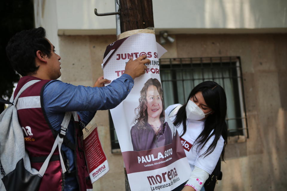 Simpatizantes de la candidata a la alcaldía del partido gobernante Morena, Paula Soto, colocan un cartel en un poste eléctrico en el último día de campaña previo a las elecciones intermedias del 6 de junio, en la Ciudad de México, el sábado 29 de mayo de 2021. (AP Foto/Ginnette Riquelme)