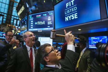 James Park (C), Fitbit CEO, takes a photograph of a screen after ringing a ceremonial bell marking the company's IPO on the floor of the New York Stock Exchange, June 18, 2015. REUTERS/Lucas Jackson