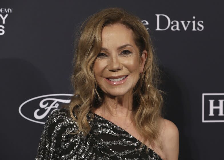 A woman with wavy blond hair smiling in a sparkly off-shoulder gown