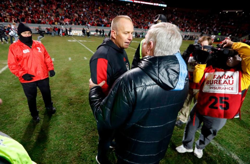 N.C. State head coach Dave Doeren greets North Carolina head coach Mack Brown after N.C. State’s 34-30 victory over UNC at Carter-Finley Stadium in Raleigh, N.C., Friday, November 26, 2021.