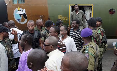 Cameroonian military personnel watch as freed hostages disembark from a military plane upon arriving at the Nsimalen International Airport in Yaounde November 26, 2014. REUTERS/Stringer