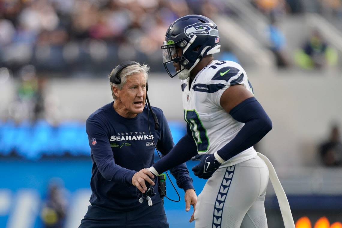 Seattle Seahawks head coach Pete Carroll greets linebacker Uchenna Nwosu (10) after the Seahawks defense made a stop on third down during the first half of an NFL football game against the Los Angeles Chargers Sunday, Oct. 23, 2022, in Inglewood, Calif. (AP Photo/Mark J. Terrill)