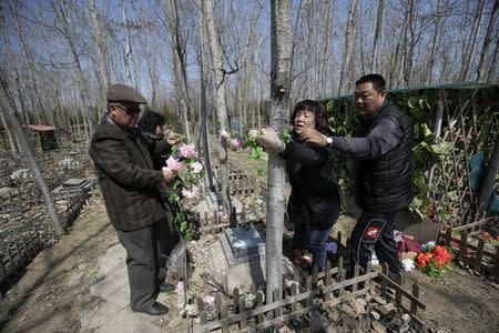A pet owner (2nd R) and her relatives set up decoration flowers for her pet dog Li Naonao at Baifu pet cemetery ahead of the Qingming Festival, also known as Tomb Sweeping Day, on the outskirts of Beijing, China March 26, 2016. REUTERS/Jason Lee