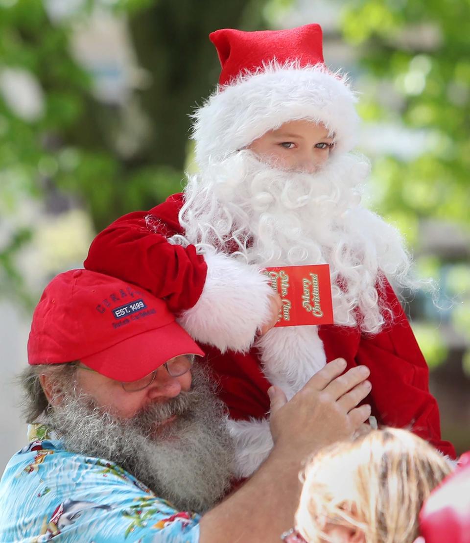 Mark Klaus, owner of Castle Noel, hoists 6-year-old Jace Palmer (aka Santa) of Valley City onto his shoulder for a photograph.