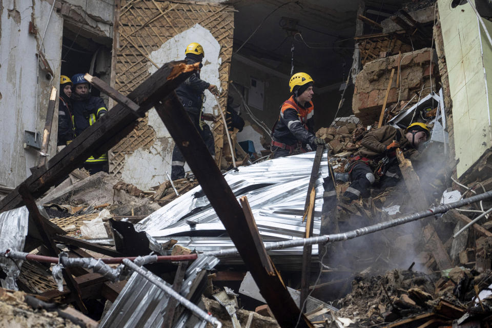 Ukrainian State Emergency Service firefighters work at the building which was destroyed by a Russian attack in Kryvyi Rih, Ukraine, Friday, Dec. 16, 2022. Russian forces launched at least 60 missiles across Ukraine on Friday, officials said, reporting explosions in at least four cities, including Kyiv. At least two people were killed by a strike on a residential building in central Ukraine, where a hunt was on for survivors. (AP Photo/Evgeniy Maloletka)