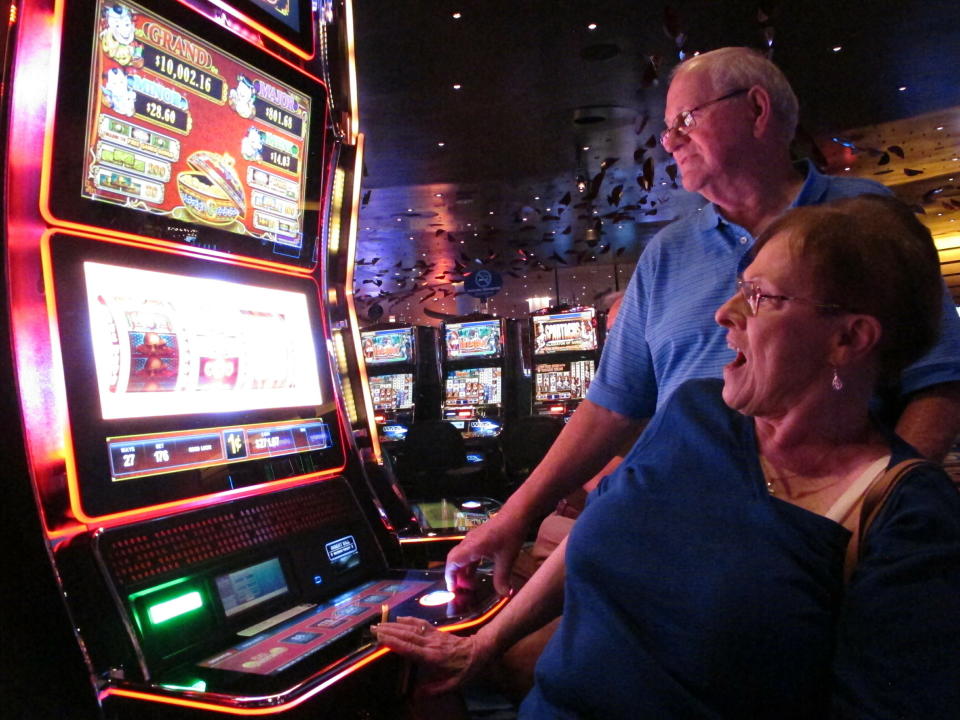 In this June 25, 2018 photo, Joyce Green of Vineland, N.J. reacts to a winning spin at a slot machine as her husband Tom looks on inside the Ocean Casino Resort in Atlantic City, N.J. The casino formerly known as Revel will turn a profit in May after months of steep losses. (AP Photo/Wayne Parry)