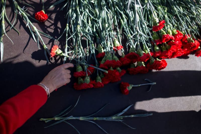 A woman reaches for a red carnation on stage, during a commemoration for the victims of the 2004 Madrid train bombings. Thousands of people in Spain attended events on Monday to mark the 20th anniversary of the worst terrorist attack in the country's history, when 10 bombs went off on full commuter trains in the Madrid region, killing 193 people and injuring almost 2,000. Luis Soto/Europapress/dpa