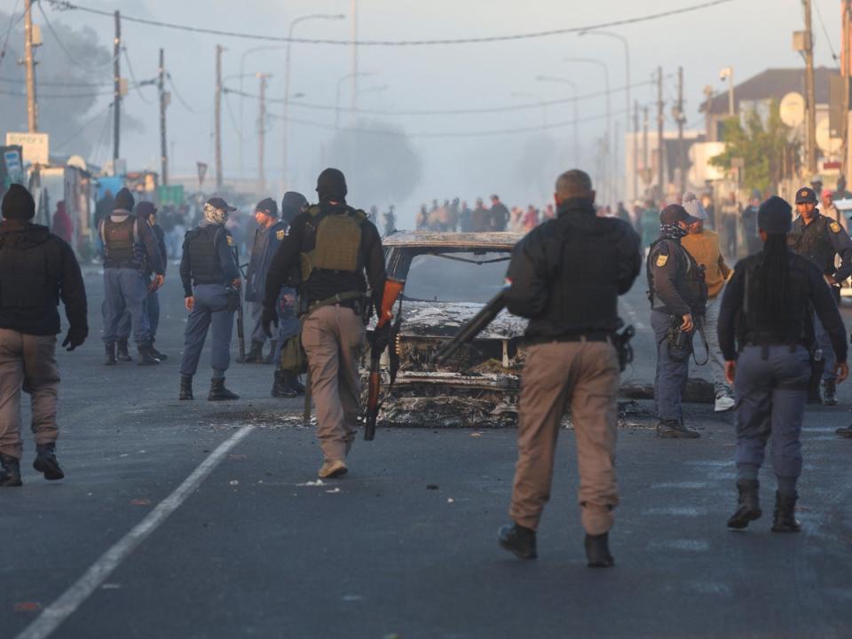 Polizeibeamte von Kapstadt stehen in Nyanga um ein ausgebranntes Fahrzeug (REUTERS/Esa Alexander)