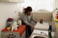 Drama school student Christina Pappa, 27, uses a washing machine at her apartment in Athens