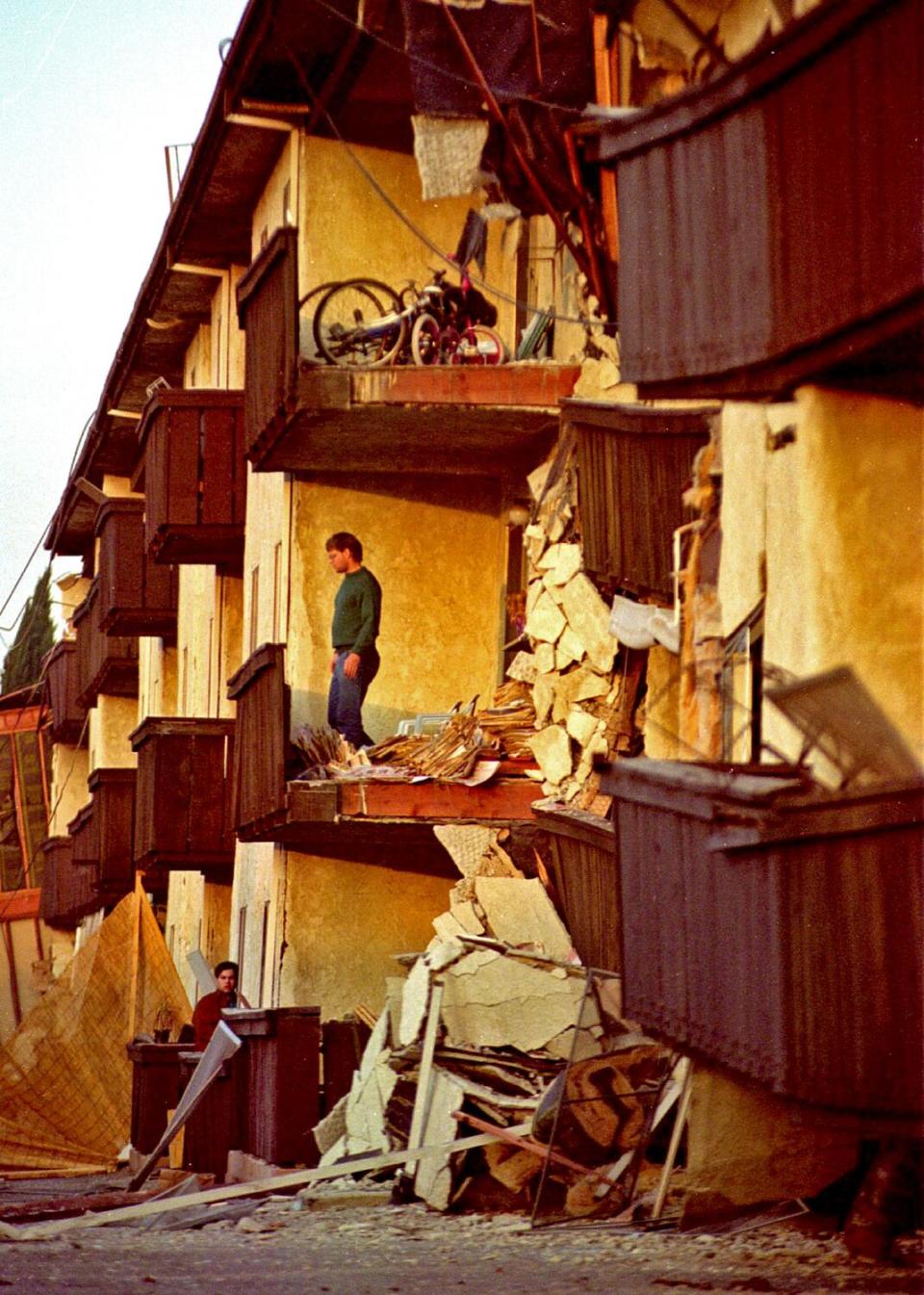 A man stares out to the street from what's left of his apartment at Northridge Meadows.