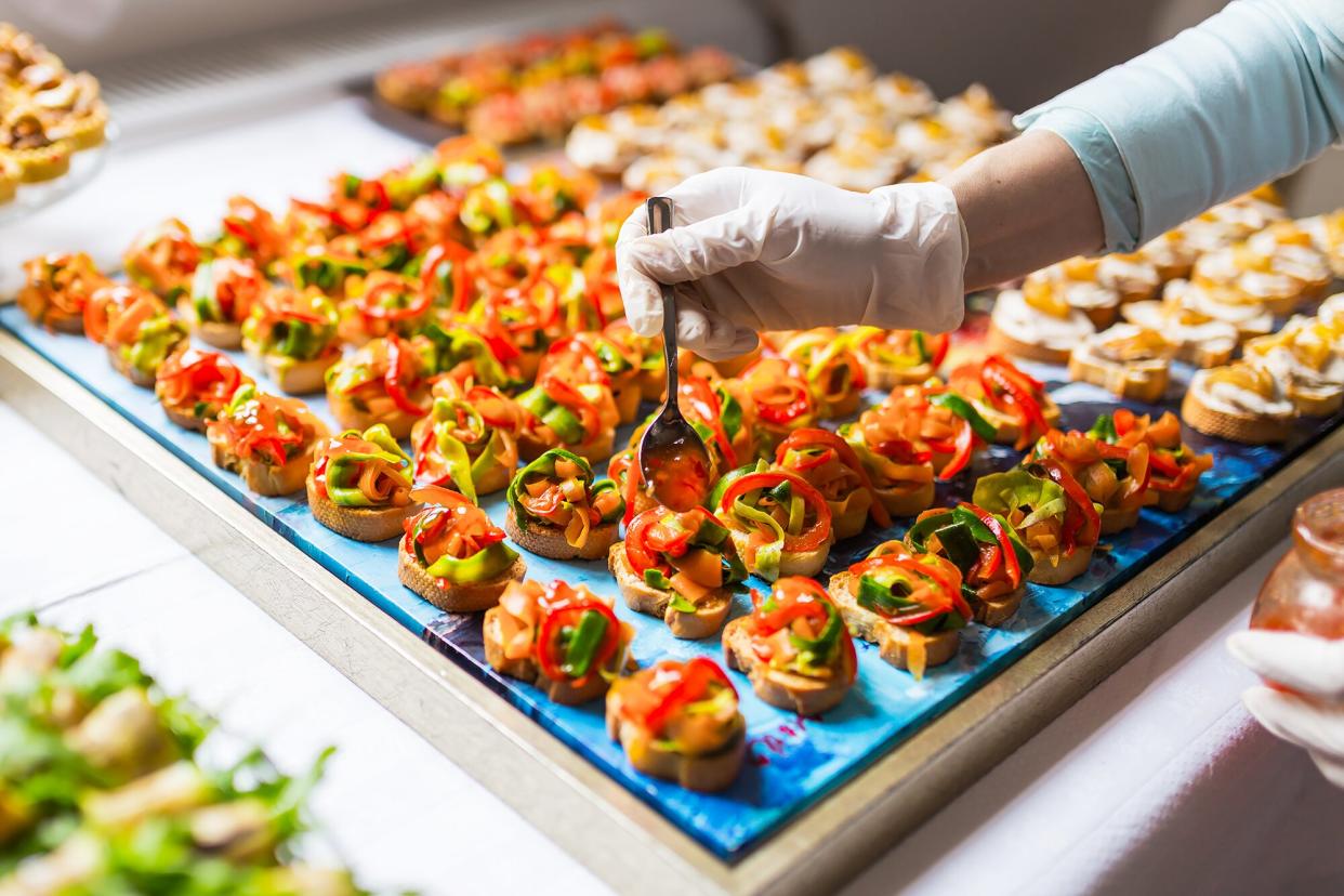 A chef places the finishing touches on a tray of canapes