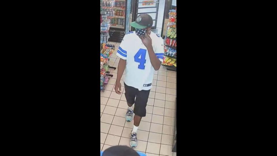 The second suspect, wearing a white Dallas Cowboys jersey, stole money from the counting machine behind the counter.