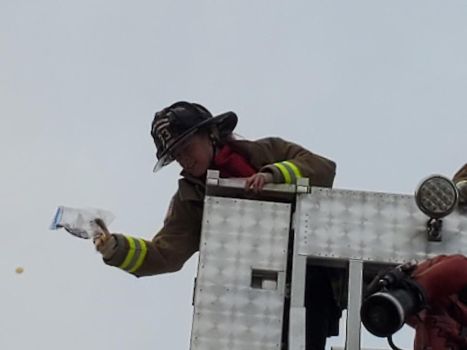 Newington firefighter Alexandria Gorski drops gelt (candy coins) to cheering children at the Mall at Fox Run in Newington Sunday Nov. 28, 2021.