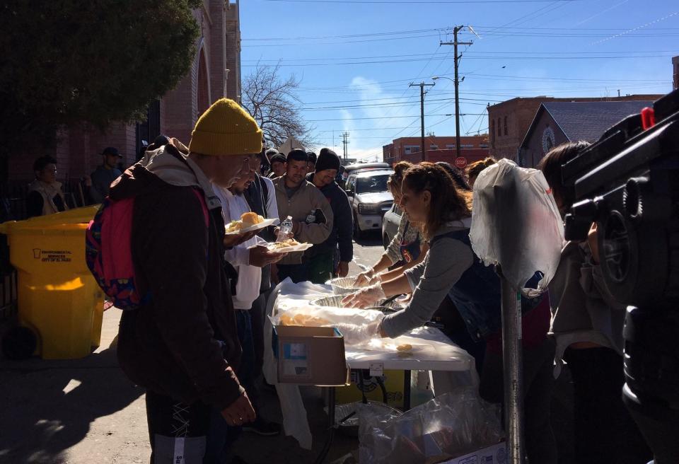 Migrants line up for lunch distribution Sunday in front of Sacred Heart Church in El Paso’s Segundo Barrio.