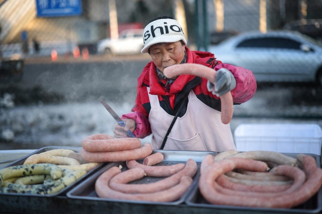 A vendor sells sausage at her stall at a market in Shenyang in northeastern China's Liaoning province on January 12, 2024. (Photo by AFP) / China OUT (Photo by STR/AFP via Getty Images)