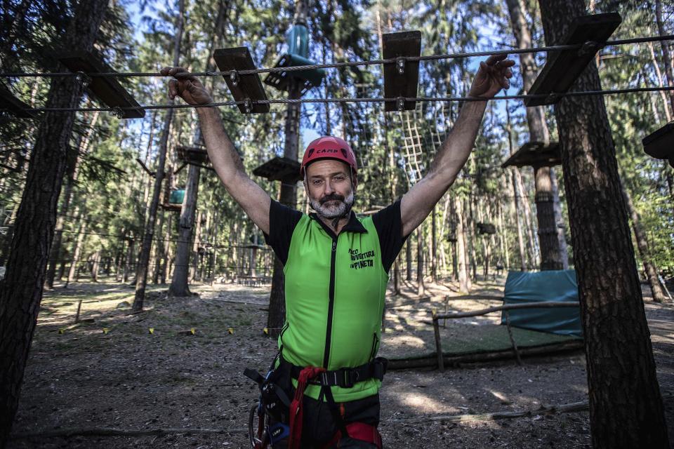 In this image take on Thursday, April 23, 2020 Diego Fregona, 58, adventure park owner, poses inside the park, in Clusone, near Bergamo, northern Italy. Fregona spent all his savings to repair the damage done to his 10.000sqm park after a whirlwind in October knocked down trees, climbing ropes and suspended trails, only to remain closed with very little money and lots of doubts as to whether he'll ever be able to restart. His words for the Associated Press were "There isn't a family who didn't have a bereavement, the only thing left to do is to get up again." (AP Photo/Luca Bruno)