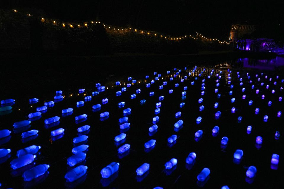 Plastic bottles coated with luminescent paint float in Waller Creek in "Inventories," an installation at the Waterloo Greenway Creek Show.