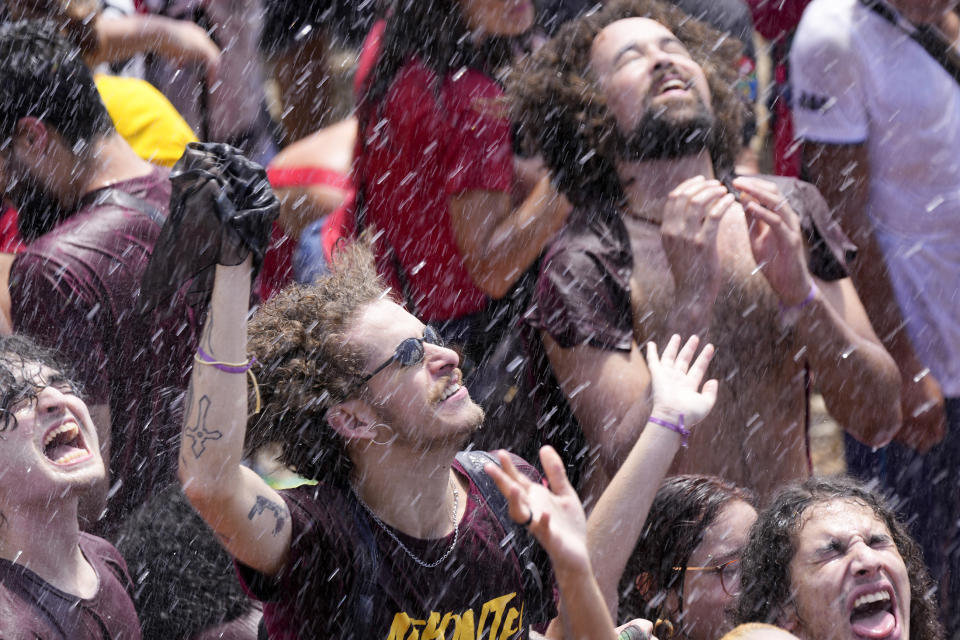 Firefighters spray water over supporters of Luiz Inacio Lula da Silva gathering to attend his inauguration as new president outside the Planalto presidential palace in Brasilia, Brazil, Sunday, Jan. 1, 2023. (AP Photo/Silvia Izquierdo)