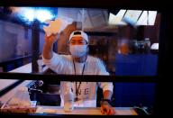 Kazuki Harada, owner of the gay bar New AO, disinfects a plastic panel which was installed to prevent infection, amid the COVID-19 outbreak, at Shinjuku Ni-chome gay district in Tokyo