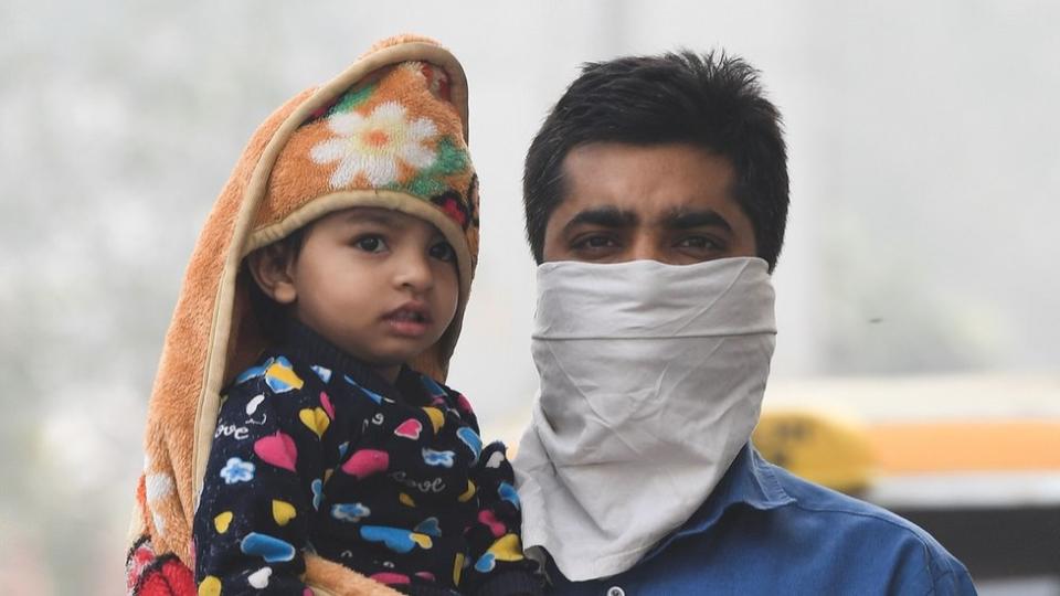 hombre con cara cubierta cargando niño