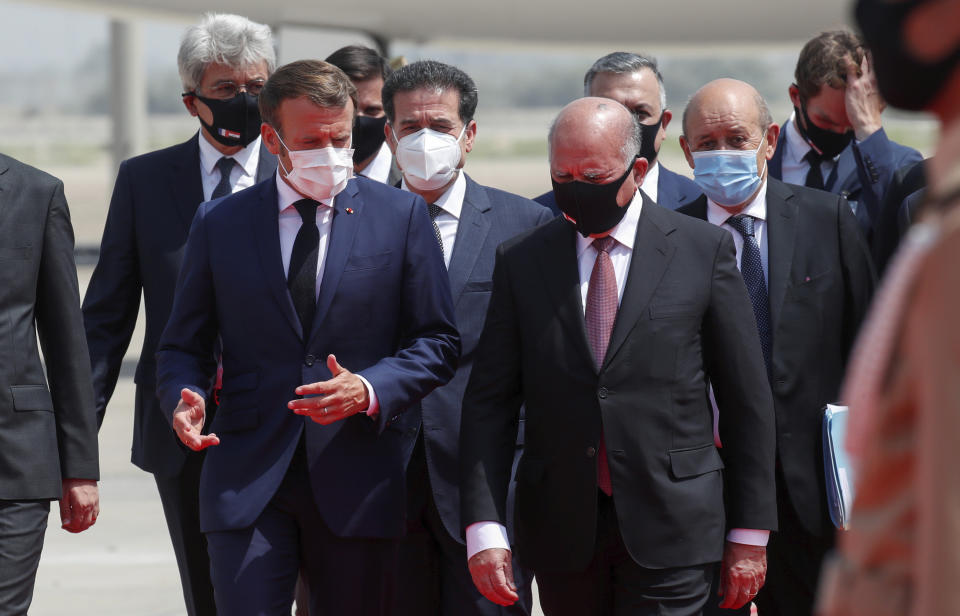 French President Emmanuel Macron, left, is welcomed by Iraq's Foreign Minister Fuad Hussein at Baghdad airport, Iraq, Wednesday, Sept. 2, 2020. Macron is the first head of state to visit the Iraqi capital since Prime Minister Mustafa al-Kadhimi, Iraq's former intelligence chief, formed a new government in May. (Gonzalo Fuentes/Pool via AP)