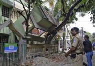 An Indian security personnel stands near a collapsed house after an earthquake in Siliguri, India, April 25, 2015. REUTERS/Stringer