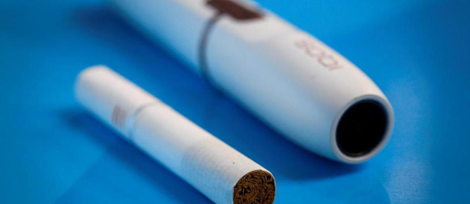 Le dispositif électronique IQOS de Philip Morris à côté d'une cigarette classique.
