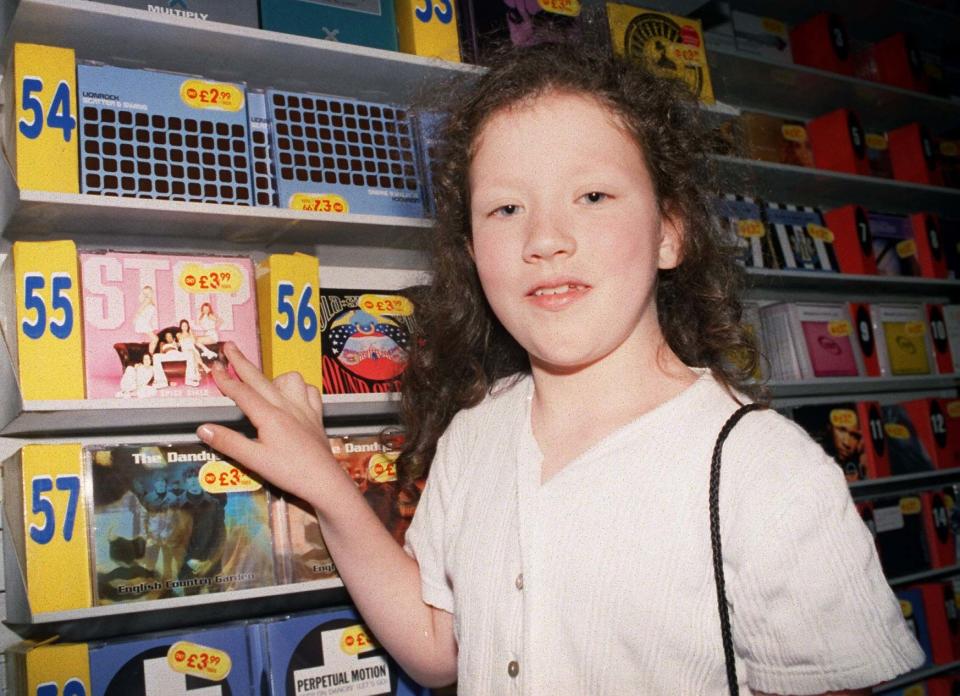 Girl pointing to CDs in a shelf organized in chart order