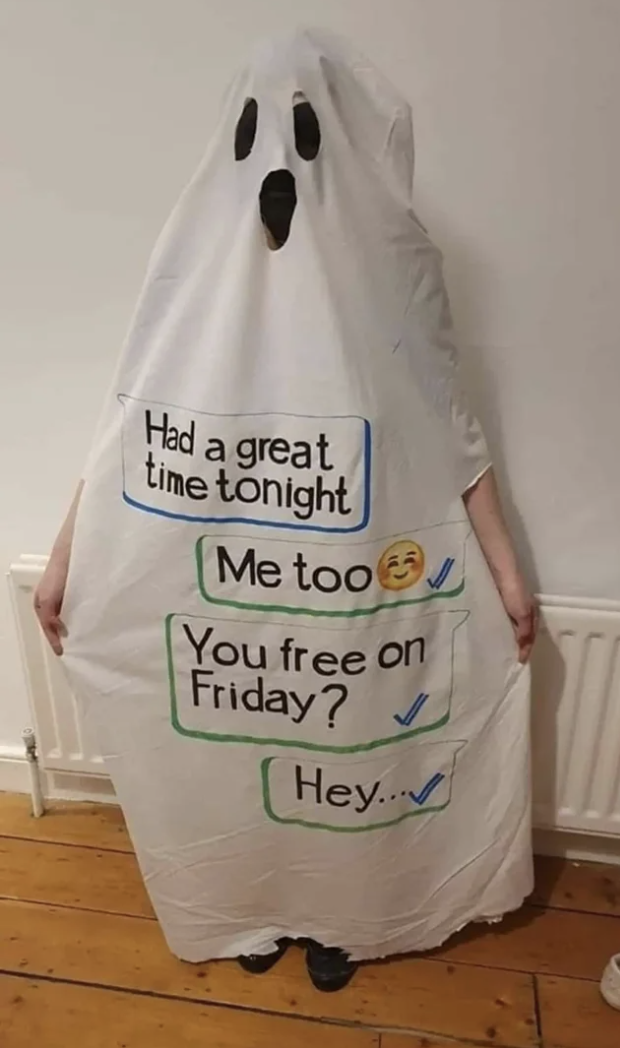 A person wearing a white sheet with eye and mouth ghost cutouts with a text exchange written on it: "Had a great time tonight," "Me too," "You free on Friday?" "Hey"