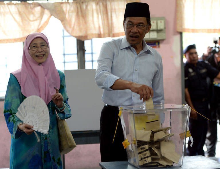 Opposition leader Anwar Ibrahim accompanied by his wife Wan Azizah (L) casts his vote at a polling station in Permatang Pauh, Penang on May 5, 2013. Millions of Malaysians voted on Sunday with one of the world's longest-serving governments under serious threat from an upstart opposition that pledges sweeping reform