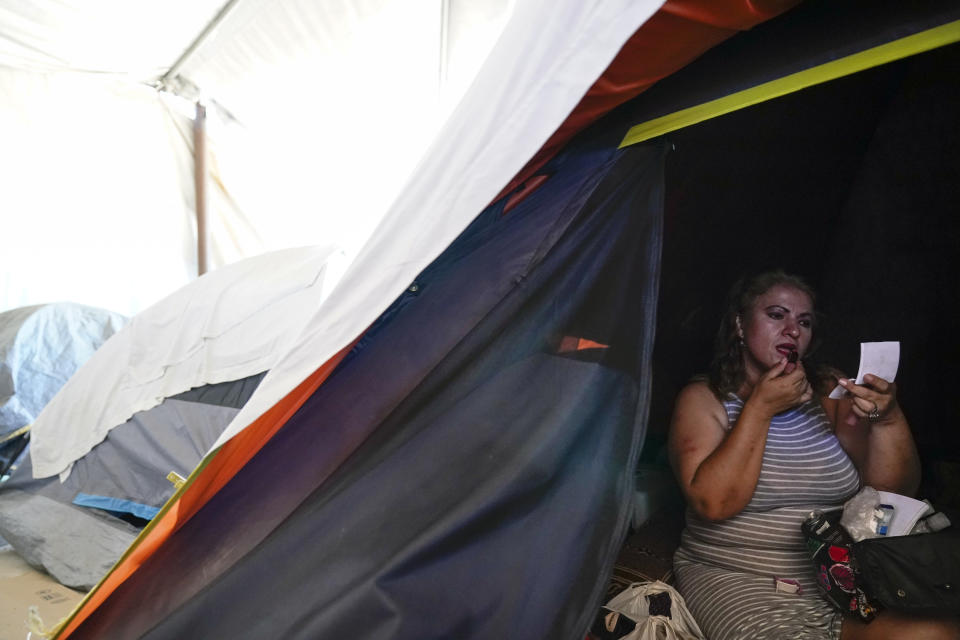 Hondurans Ana Morazan applies makeup inside her tent a migrant shelter Thursday, June 30, 2022, in the border city of Tijuana, Mexico. Back-to-back hurricanes destroyed her home in Honduras in 2020, forcing her and Juarez to join the millions of people uprooted by rising seas, drought, searing temperatures and other climate catastrophes. (AP Photo/Gregory Bull)