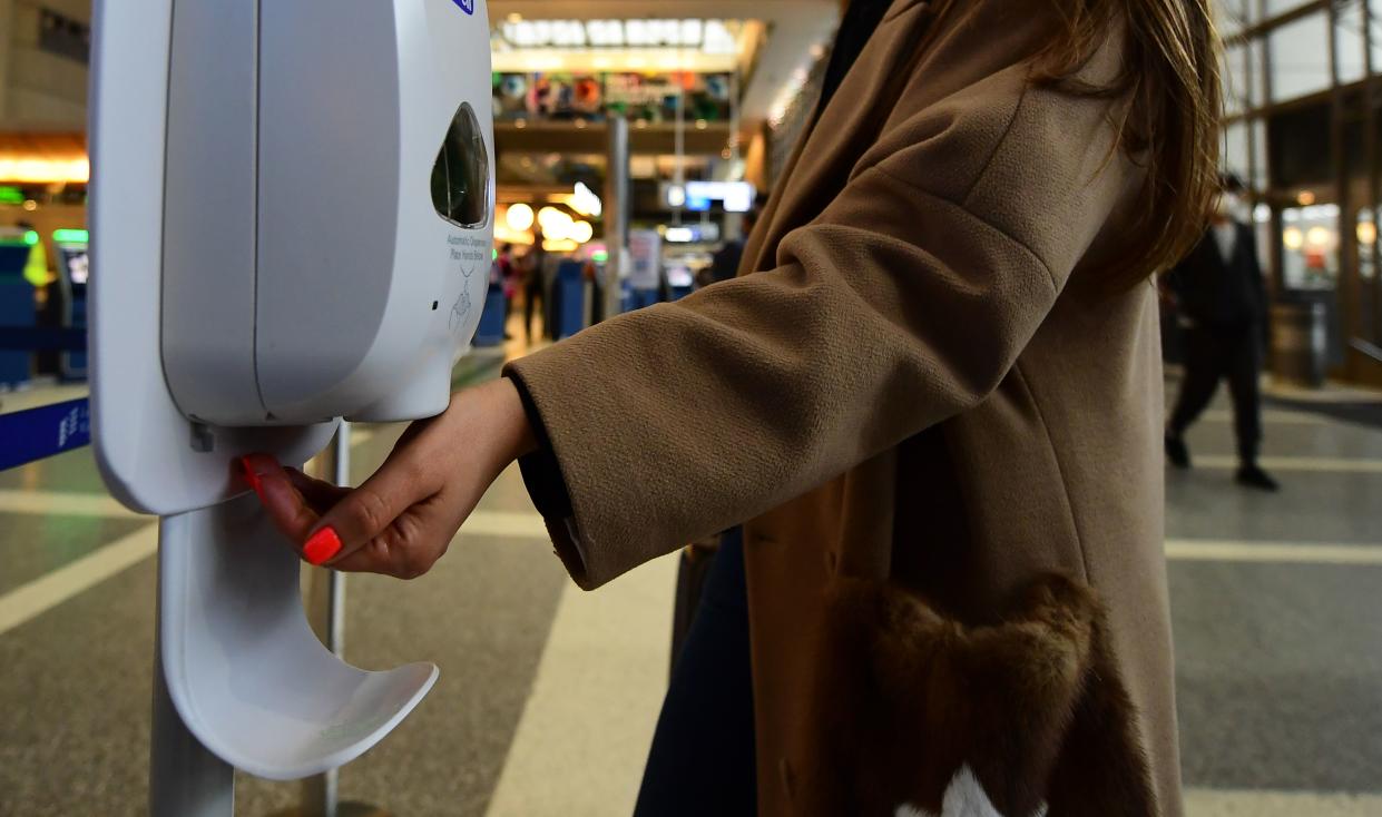 A woman uses hand sanitizer at Los Angeles International Airport on March 12, 2020 one day before a US flight travel ban hits 26 European countries amid ongoing precautions over the Coronavirus. - US President Donald Trump announced a shock 30-day ban on travel from mainland Europe over the coronavirus pandemic that has sparked unprecedented lockdowns, widespread panic and another financial market meltdown Thursday.The announcement came as China, where the outbreak that first emerged in December, showed a dramatic drop in new cases and claimed "the peak" of the epidemic had passed. (Photo by Frederic J. BROWN / AFP) (Photo by FREDERIC J. BROWN/AFP via Getty Images)