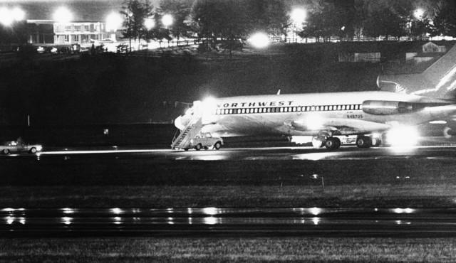 A Northwest Airlines jet, its lights on in the dark, sits on a runway.