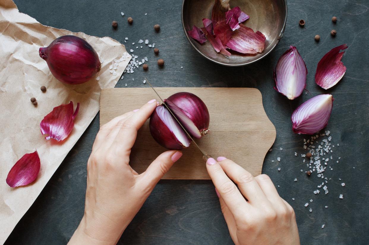 a photo of some cutting an onion on a cutting board