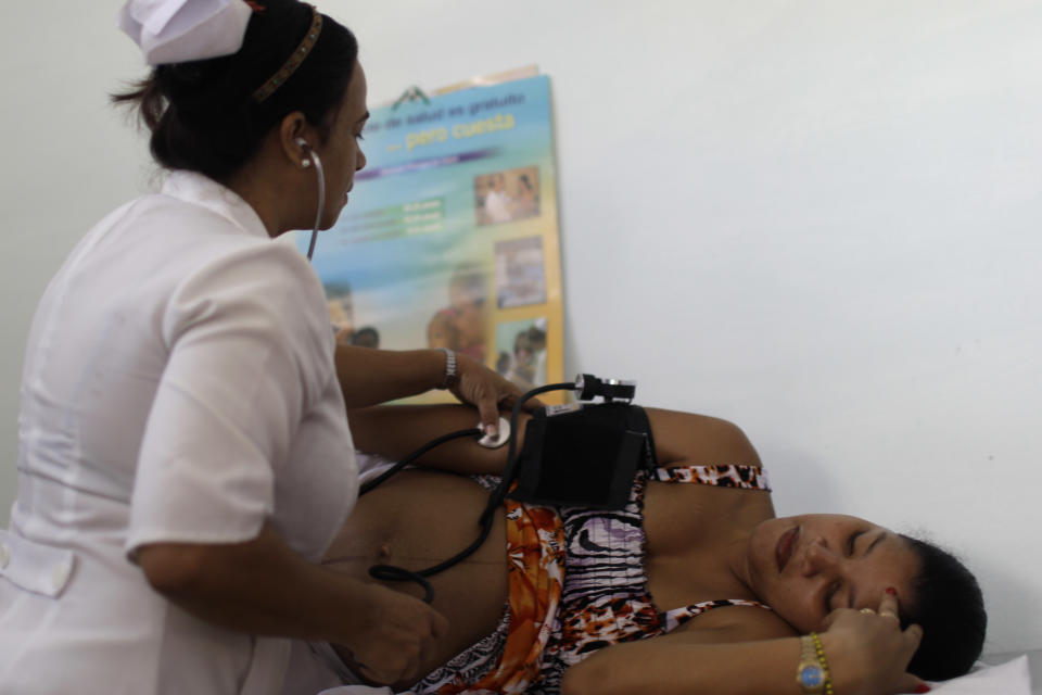 In this Aug 16, 2012 photo, a nurse checks the blood pressure of patient Niurka Rodriguez, who is eight months pregnant at a government run neighborhood clinic in Havana, Cuba. Cuba's system of free medical care, long considered a birthright by its citizens and trumpeted as one of the communist government's great successes, is not immune to cutbacks under Raul Castro's drive for efficiency. The health sector has already endured millions of dollars in budget cuts and tens of thousands of layoffs, and Castro is looking for more ways to save. (AP Photo/Franklin Reyes)